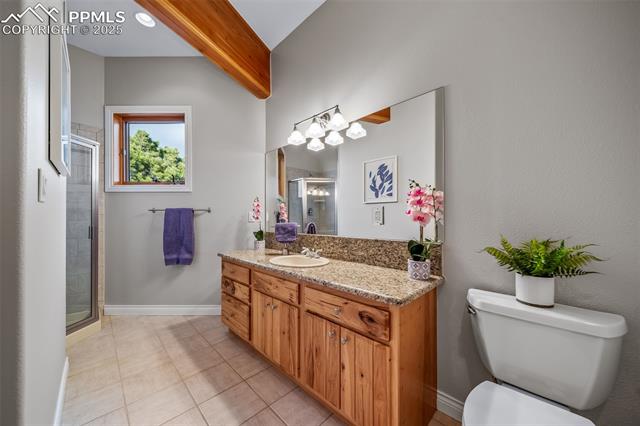 4586 East Best Road Larkspur, CO 80118 - Photo 17 of 50 Bathroom with vanity, a shower stall, light tile patterned floors, and beam ceiling