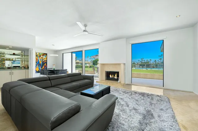a living room with furniture a flat screen tv and a floor to ceiling window