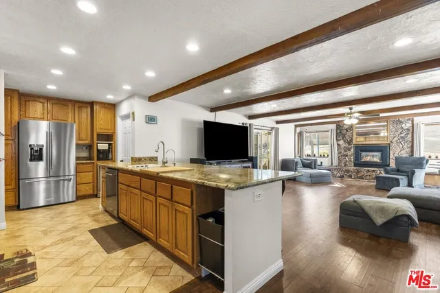 a open kitchen with stainless steel appliances granite countertop a sink dishwasher stove and refrigerator with wooden floor