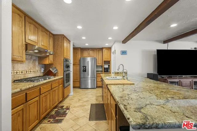 a large kitchen with kitchen island granite countertop a large counter top stainless steel appliances and cabinets