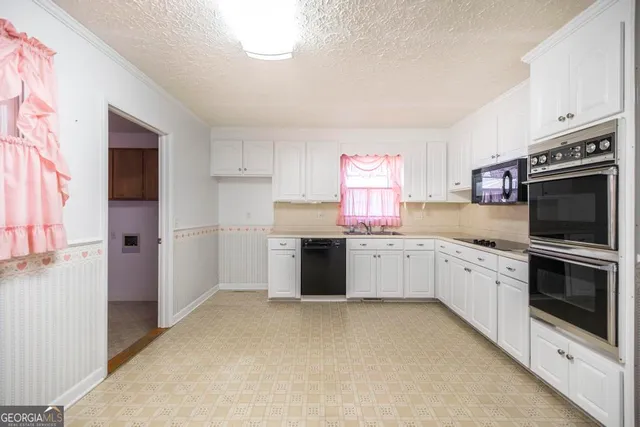 a kitchen with granite countertop a dining table chairs and a refrigerator