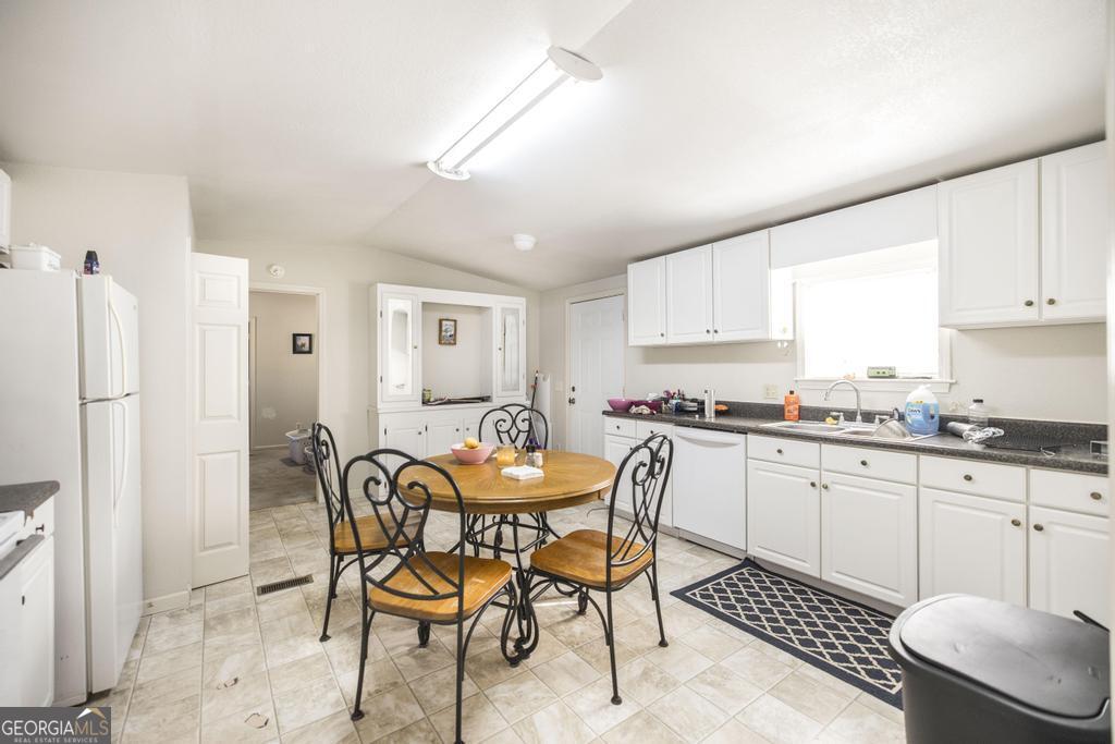 172 Old Eastman Road Cochran, GA 31014 - Photo 38 of 60 a kitchen with granite countertop a dining table chairs and a refrigerator