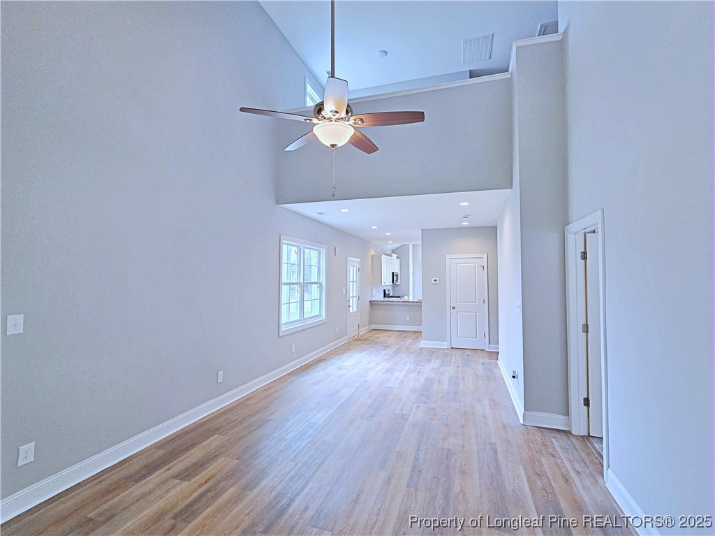 940 Kensington Park Road Fayetteville, NC 28311 - Photo 5 of 41 an empty room with wooden floor chandelier fan and windows