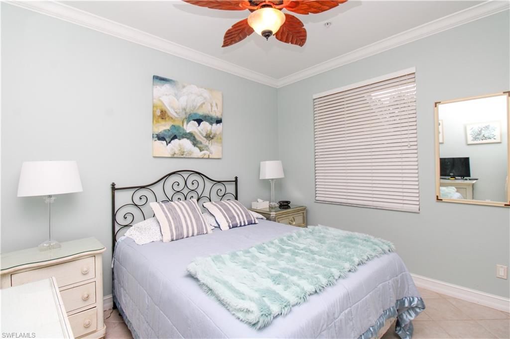 817 Carrick Bend Circle, Unit 101 Naples, FL 34110 - Photo 17 of 49 a bedroom with a large bed and a lamp on dresser