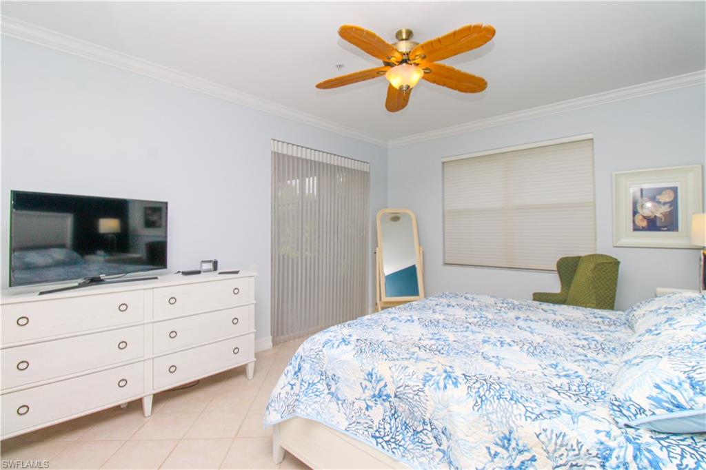 817 Carrick Bend Circle, Unit 101 Naples, FL 34110 - Photo 38 of 49 a bedroom with a bed a flat screen tv and dresser