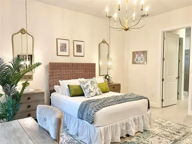 a bedroom with a bed a couch and potted plant on the dresser