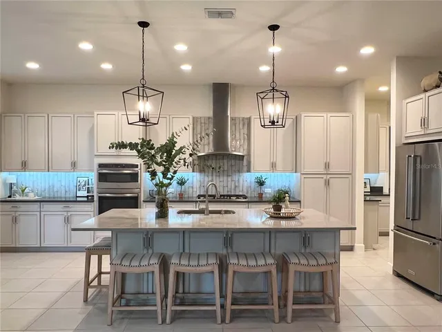 a kitchen with refrigerator a center island a stove and a wooden floor
