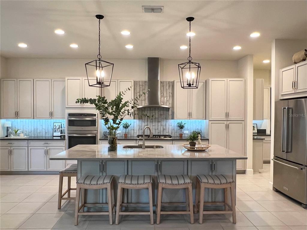 2337 Clemblue Road Clermont, FL 34715 - Photo 6 of 33 a kitchen with refrigerator a center island a stove and a wooden floor