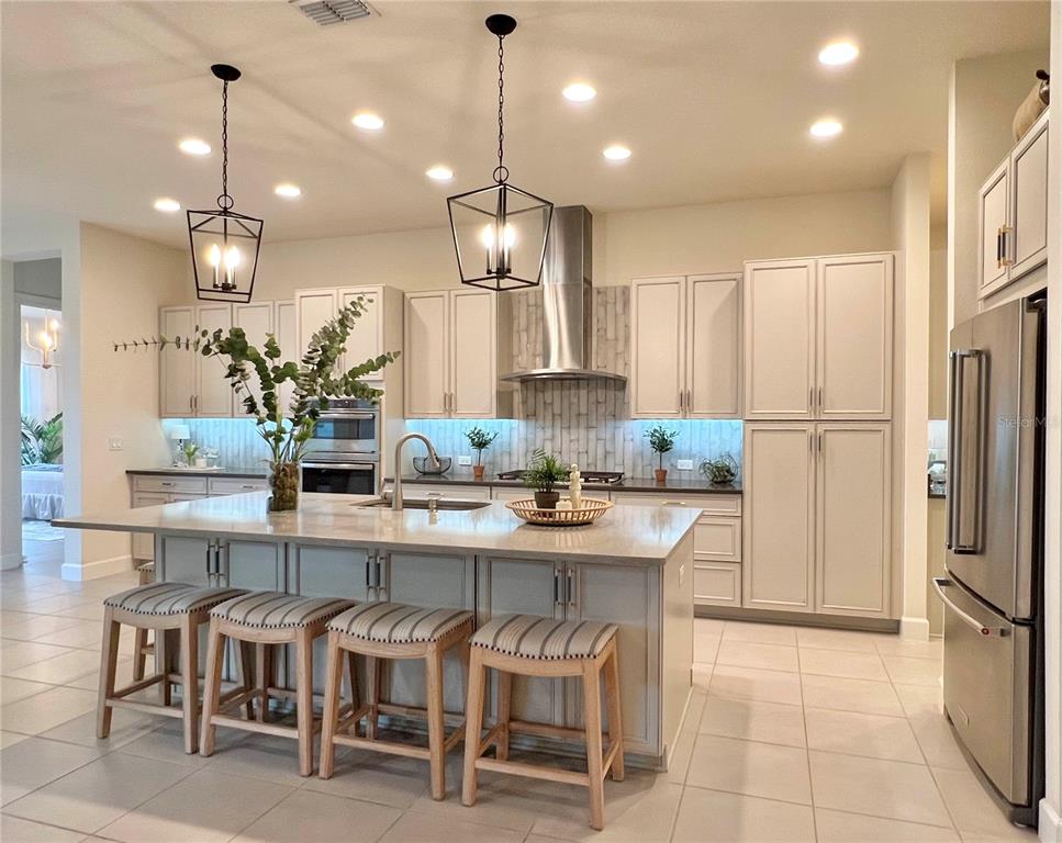 2337 Clemblue Road Clermont, FL 34715 - Photo 7 of 33 a kitchen with kitchen island stainless steel appliances a table chairs refrigerator and microwave