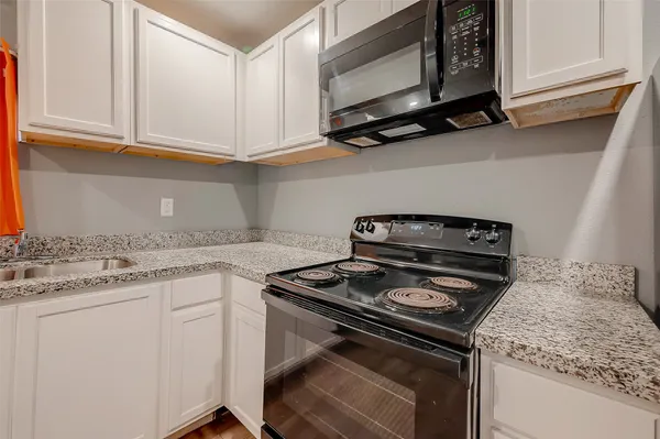 a kitchen with granite countertop white cabinets and a stove top oven
