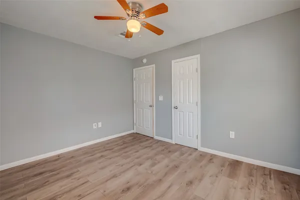 an empty room with wooden floor a ceiling fan and closet area