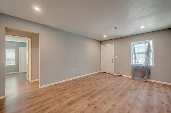 an empty room with wooden floor and windows