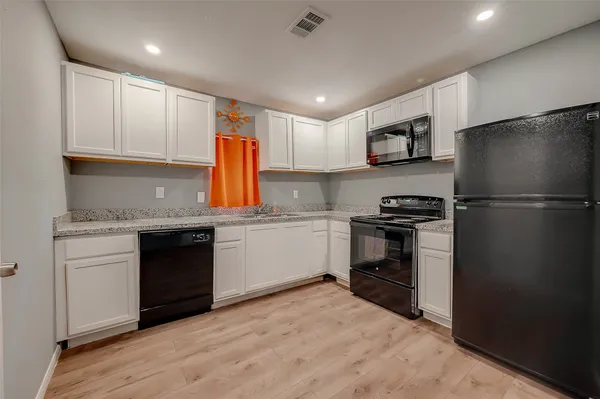 a kitchen with granite countertop a refrigerator stove top oven and sink