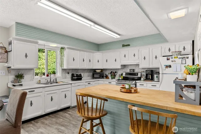 a kitchen with a sink a stove cabinets and wooden floor