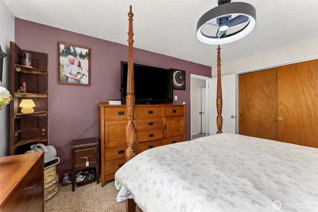 a bedroom with a bed and a flat tv screen on dresser