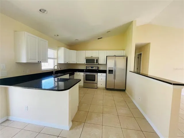 a kitchen with stainless steel appliances granite countertop a sink a stove a refrigerator a microwave and cabinets