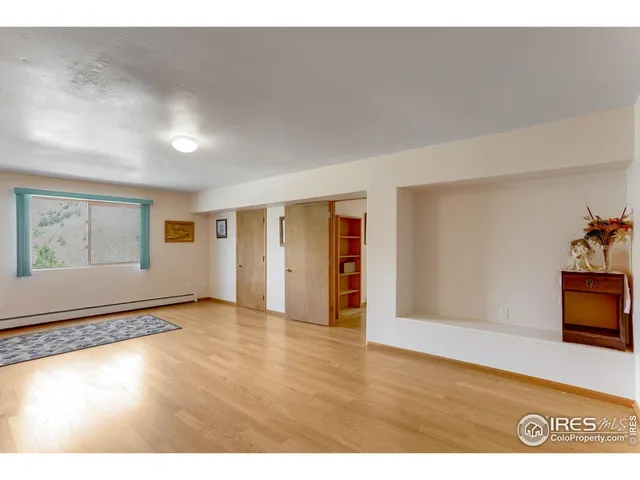 a view of a bedroom with wooden floor and window