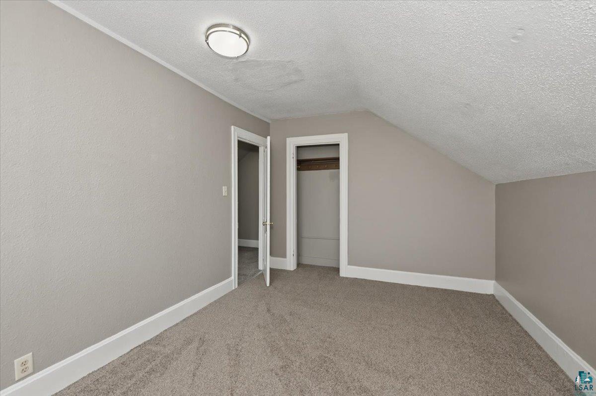 5319 East 3rd Street Superior, WI 54880 - Photo 29 of 33 Carpeted room featuring neutral-toned walls, white trim, and a sloped ceiling