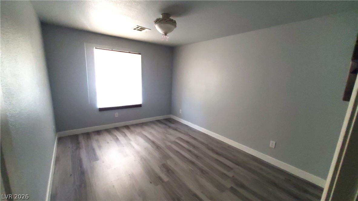 7903 Dell Ridge Avenue Las Vegas, NV 89179 - Photo 15 of 20 A well-lit bedroom featuring durable plank flooring and a classic overhead light fixture.