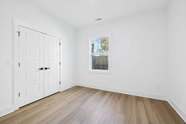 a view of an empty room with wooden floor and a window