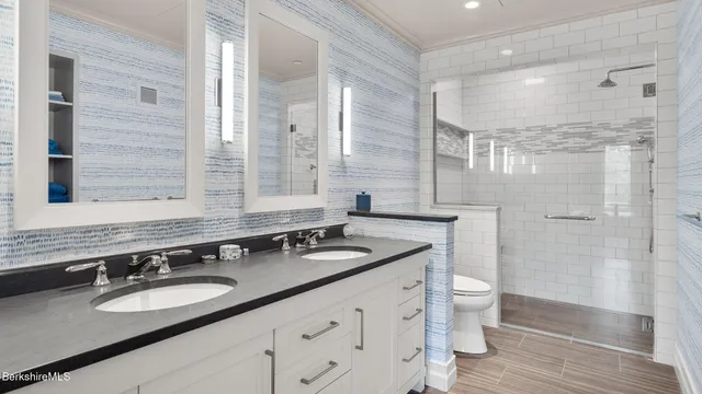 a bathroom with a granite countertop sink a toilet a mirror and shower