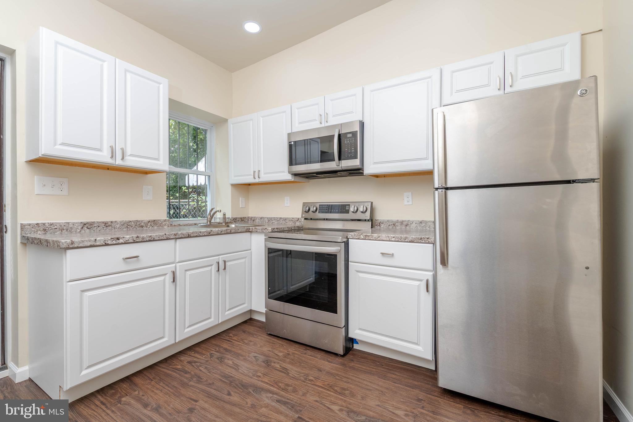1839 Ramsay Street Baltimore, MD 21223 - Photo 7 of 22 a white refrigerator freezer sitting inside of a kitchen with stainless steel appliances granite countertop a refrigerator stove a sink and dishwasher with wooden floor