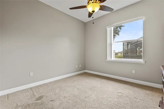 an empty room with a window and a ceiling fan