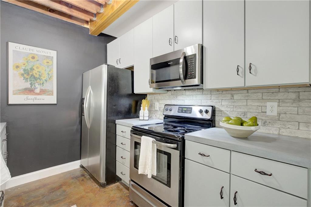 172 Carroll Street Southeast, Unit 103 Atlanta, GA 30312 - Photo 9 of 24 a kitchen with stainless steel appliances granite countertop a refrigerator a stove a microwave a sink and cabinets