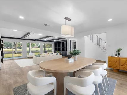 a kitchen with stainless steel appliances kitchen island granite countertop a stove top oven a sink dishwasher a refrigerator and a dining table with wooden floor