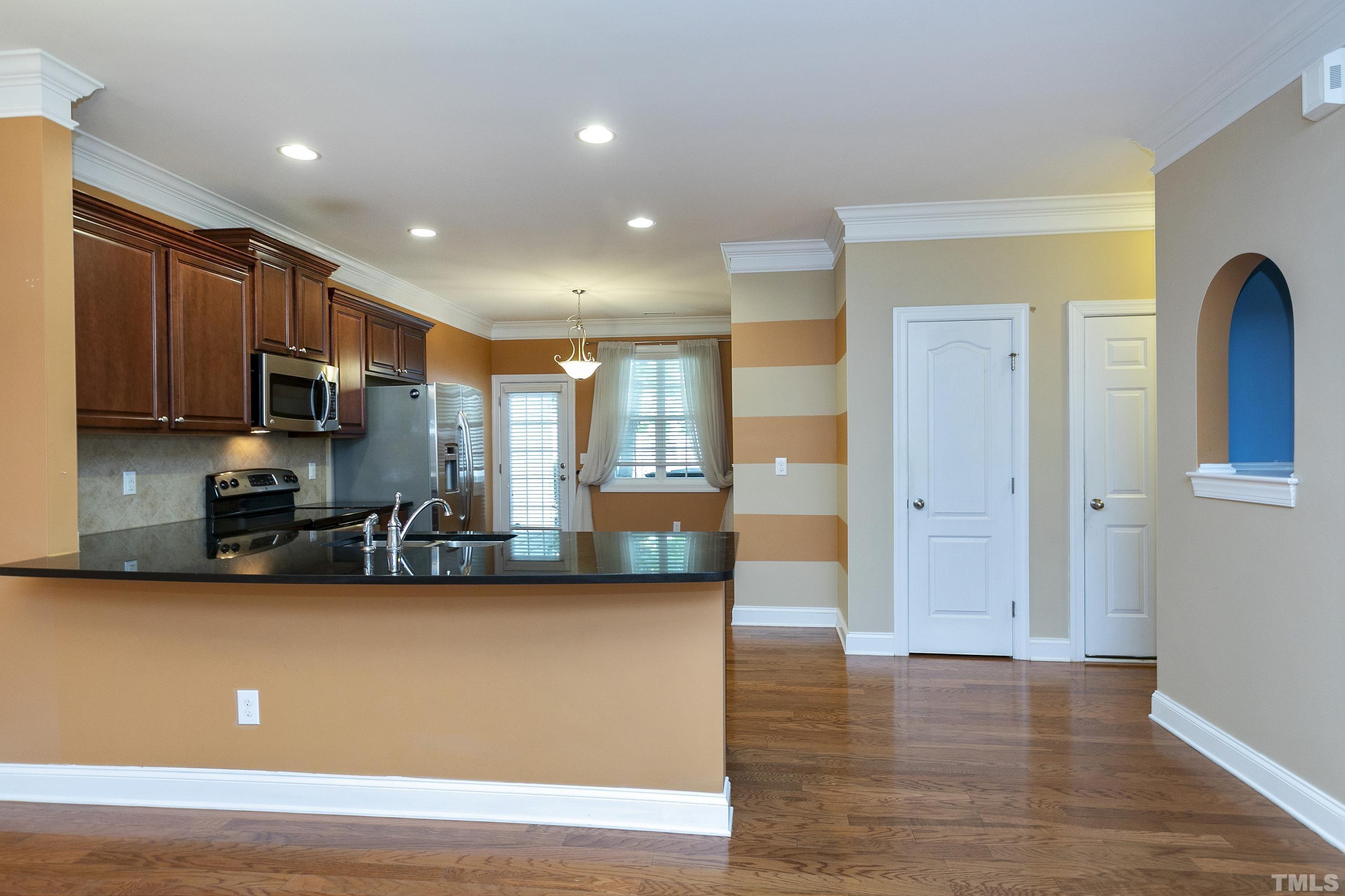 634 Democracy Street Raleigh, NC 27603 - Photo 8 of 43 a view of a kitchen with kitchen island a sink wooden floor and black appliances