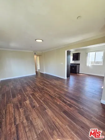 a view of empty room with wooden floor and window