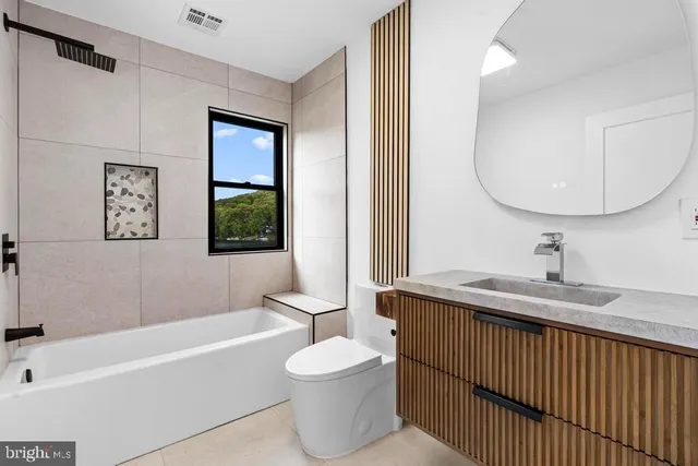 a bathroom with a granite countertop sink toilet a mirror and bathtub
