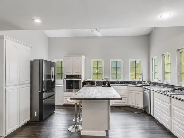 a kitchen with granite countertop stainless steel appliances a sink stove refrigerator and cabinets