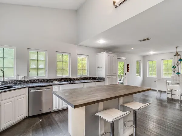 a view of kitchen island wooden floor center island stainless steel appliances and windows