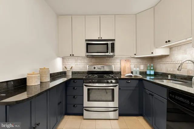 a kitchen with granite countertop white cabinets and stainless steel appliances