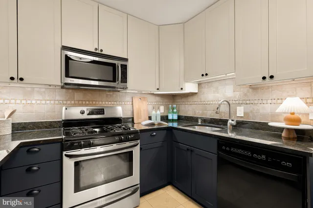 a kitchen with stainless steel appliances granite countertop grey cabinets a stove a sink and dishwasher