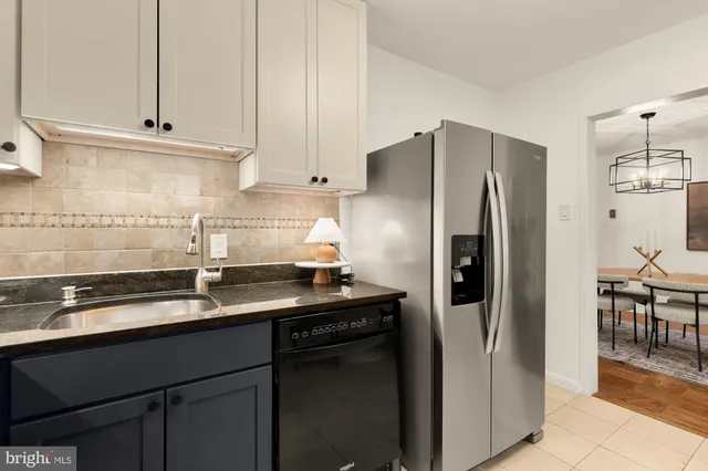 a kitchen with stainless steel appliances granite countertop a refrigerator a sink and white cabinets