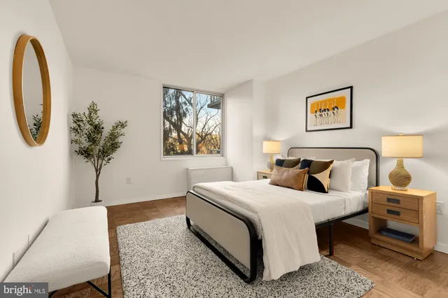 a bedroom with a bed a painting on the wall and a potted plant