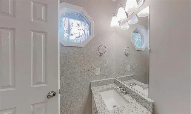 a bathroom with a granite countertop sink a mirror and a bathtub