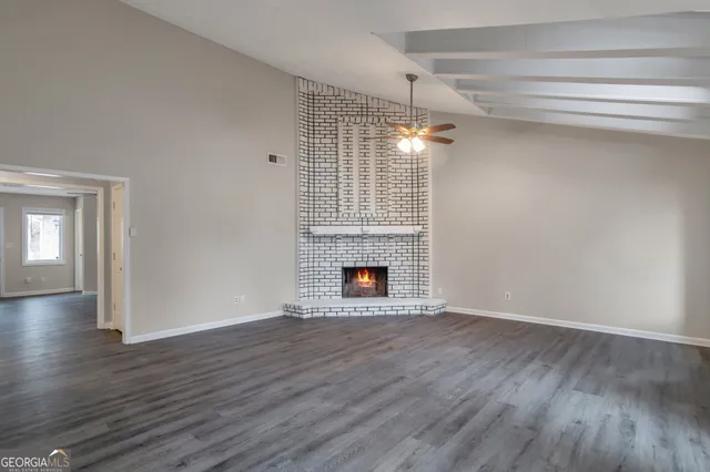 a view of an empty room with wooden floor fireplace and a window