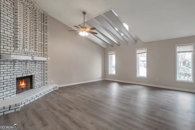 a view of an empty room with wooden floor fireplace and a window
