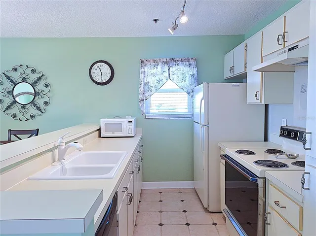 a kitchen with a refrigerator a stove and white cabinets