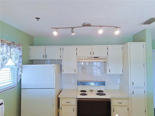a view of a kitchen with a sink and a refrigerator