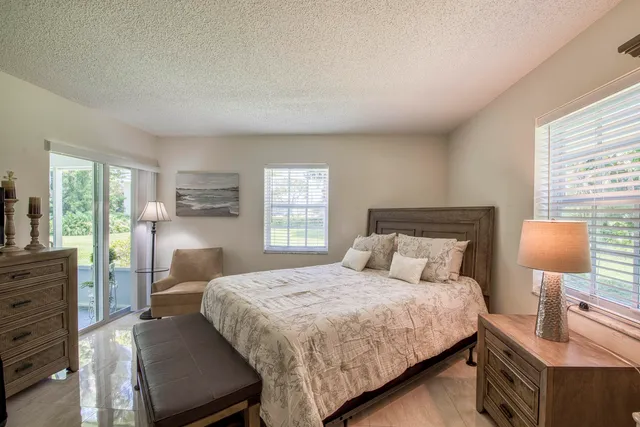 a bedroom with a bed a lamp and a large window