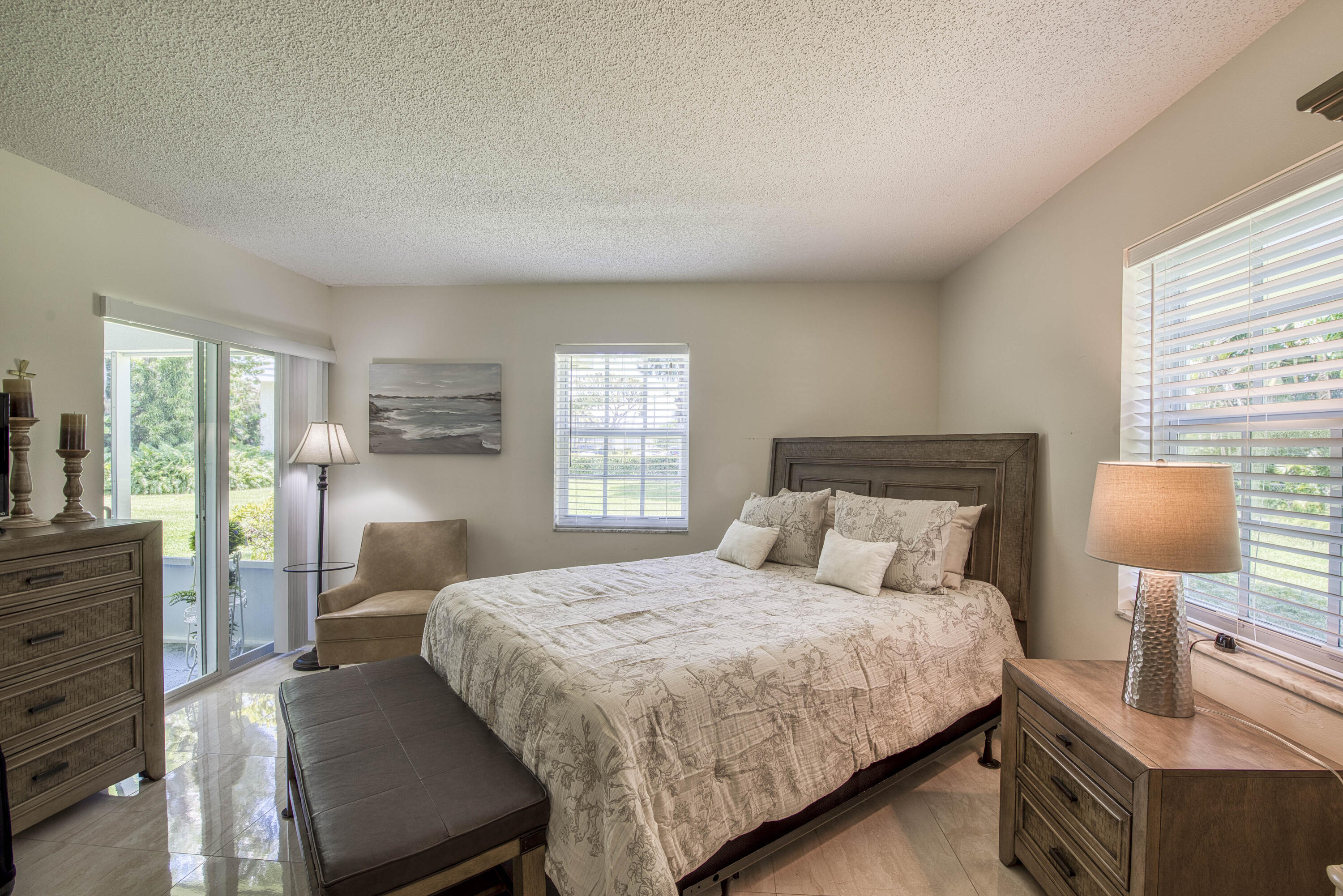 1205 Sandy Lane, Unit 149 Singer Island, FL 33404 - Photo 19 of 28 a bedroom with a bed a lamp and a large window