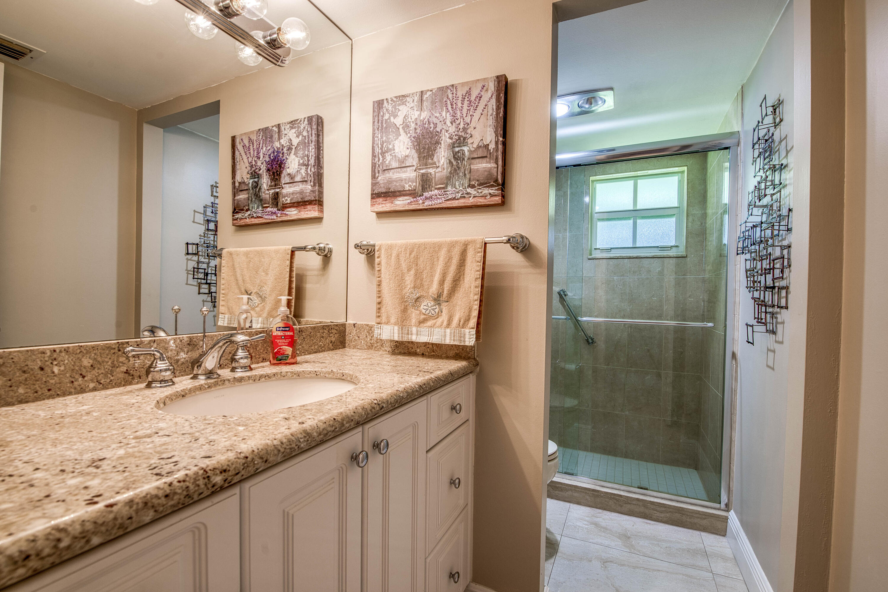 1205 Sandy Lane, Unit 149 Singer Island, FL 33404 - Photo 24 of 28 a bathroom with a granite countertop sink a mirror and a shower