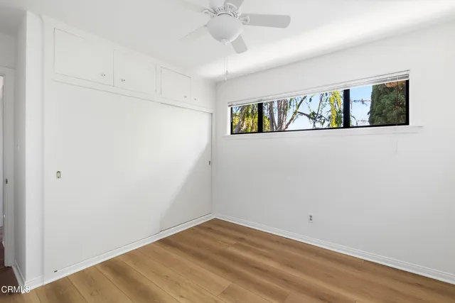 a view of an empty room with window and wooden floor