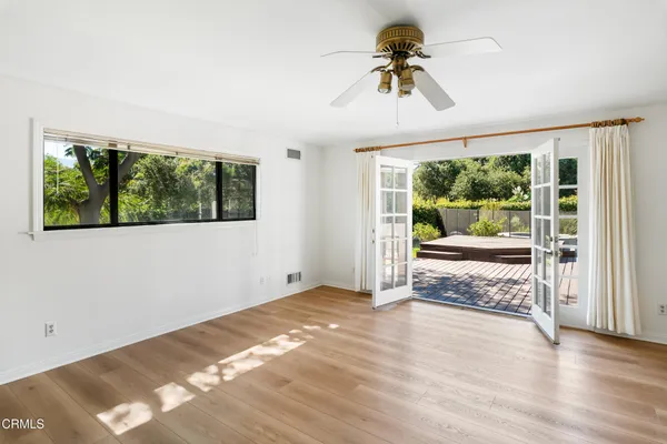 a view of a big room with wooden floor a ceiling fan and windows