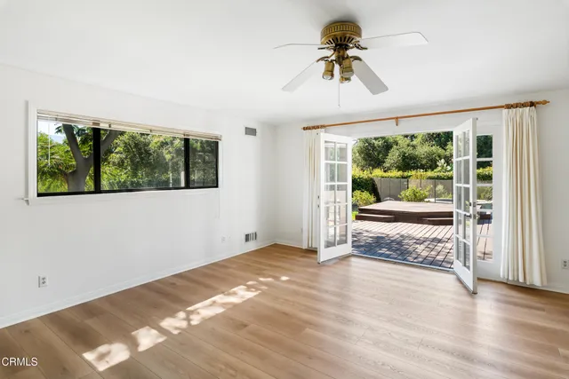 a view of a big room with wooden floor a ceiling fan and windows