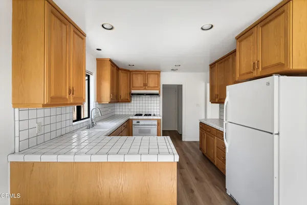 a kitchen with a refrigerator a stove top oven a sink and cabinets